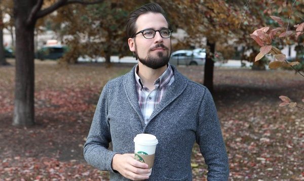 Mr. Autumn Man Walking Down Street With Cup Of Coffee, Wearing Sweater Over Plaid Collared Shirt
